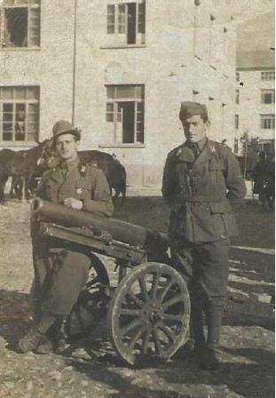 Italia, 1940-1943. Enrico Silvestri (primo a sx), con cappello alpino, nei pressi di un pezzo d'artiglieria da montagna (cannone da 65/17 mod. 1908/1913) e assieme a un commilitone